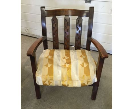 An Arts & Crafts style nursing chair with a gold/cream cushion.