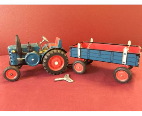 A wind-up tinplate blue tractor and trailer, in working order