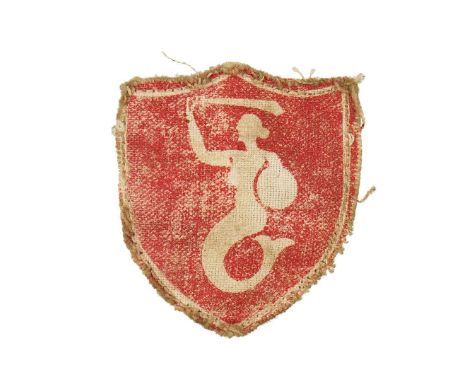 A shield-shaped patch made of red material. There is a white shield around it, in the middle of the shield there is a white m