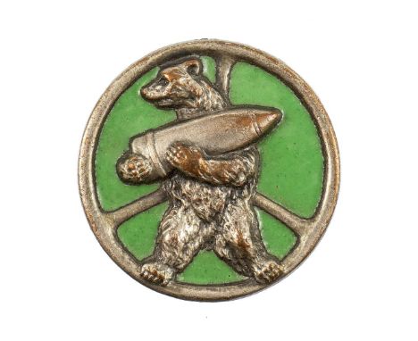 Badge in the form of a steering wheel, with a bear holding an artillery shell, green enamelled background. Smooth reverse wit