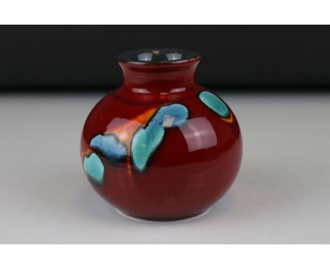 A late 20th century red ground Poole Pottery vase of squat form, 10 cm tall. 