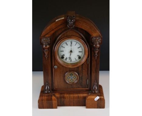 19th century Mantle Clock, the domed top Rosewood Case carved with Face Masks, the white enamel face with Roman numerals, wit