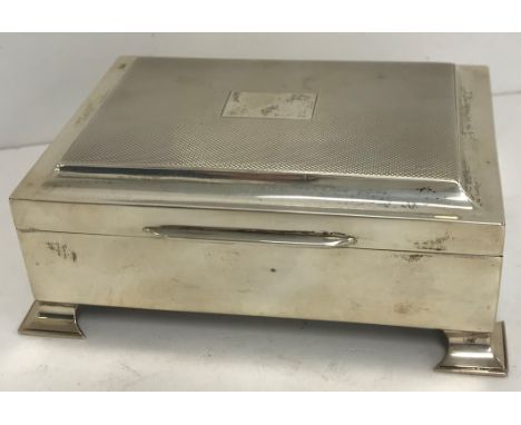 A modern silver cigarette box with engine-turned decoration, raised on splayed bracket feet (Birmingham 1961
