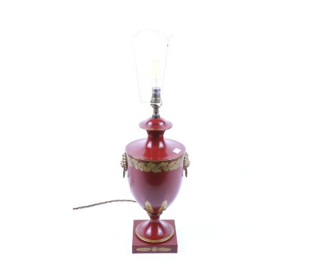 A contemporary red lacquered metal urn shaped table lamp. With lion head handles and gilt foliage decoration, mounted on a sq