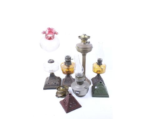 A group of assorted vintage oil lamps and spare parts. Including four glass chimneys, five cast metal pyramid bases, a gradua