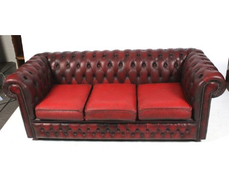 A vintage ox blood leather Chesterfield sofa. With scroll supports, button back with studded details, mounted on mahogany fee