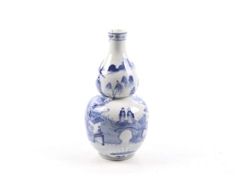 A Chinese blue and white gourd shaped vase. Decorated with pavilions and figures in a rocky landscape. Apocryphal four charac