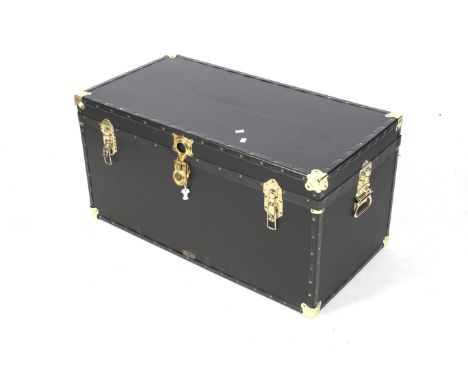 A contemporary Mossman black travel trunk. With brass fittings and corners, keys present. L101cm x D52cm x H51cm