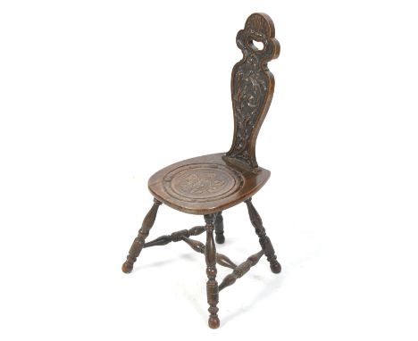 A vintage carved oak spinning chair. The back with raised pattern of trailing leaves, the seat with a round carving of leaves