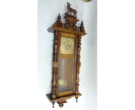 A WALNUT CASED VIENNA WALL CLOCK, the crest with composition deer mount, brass dial with Arabic numerals, the pendulum with e