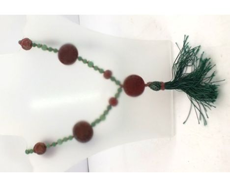 A CINNABAR DISC AND JADE BEAD NECKLACE comprising seven discs, two Buddhas and two carved beads with tassels below (overall d