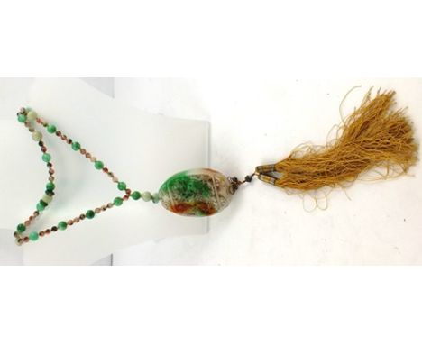 A LATE 19TH CENTURY VARIEGATED JADE NECKLACE of large and small beads, suspending a large carved oval pendant with tassels be