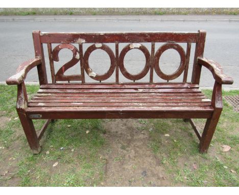 A heavy gauge stained and weathered teak three seat garden bench to commemorate the millennium, limited edition number 0266/2
