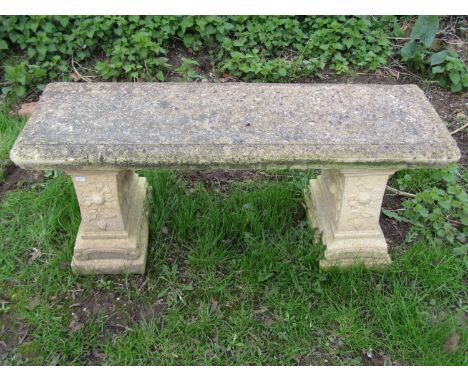 A weathered cast composition stone three sectional garden bench with rectangular slab seat raised on stepped supports with fr