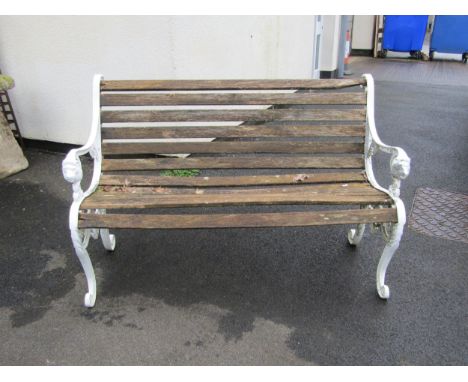 A two seat garden bench with weathered slatted   seat raised on decorative painted cast alloy end supports with scrolled deta