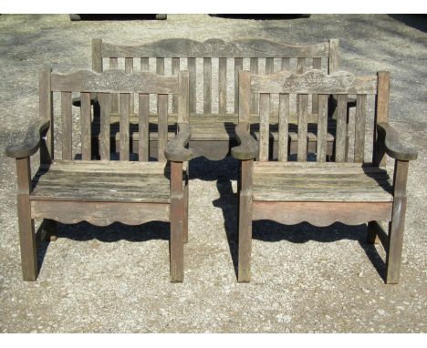 A Bridgman &amp; Co Ltd stained and weathered teak three seat garden bench 161 cm wide and a pair of matching open armchairs 