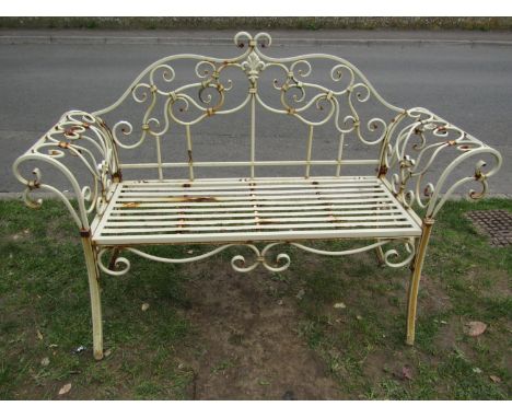 A weathered cream painted two seat metal bench loosely in the Regency style with shaped outline and open scrolled detail, str