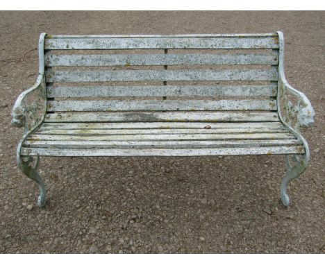 A weathered light blue/cream painted garden bench with slatted seat raised on decorative pierced and scrolled cast iron end s