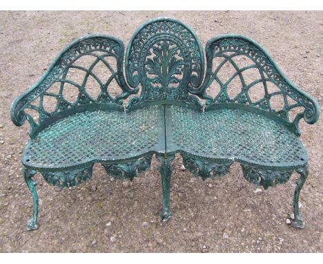 A weathered green painted cast alloy garden bench with shaped outline and decorative pierced lattice, anthemion and geometric