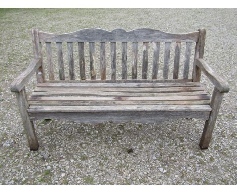 A Bridgman weathered teak three seat garden bench with slatted seat and back beneath a shaped rail with acorn and oak leaf ca
