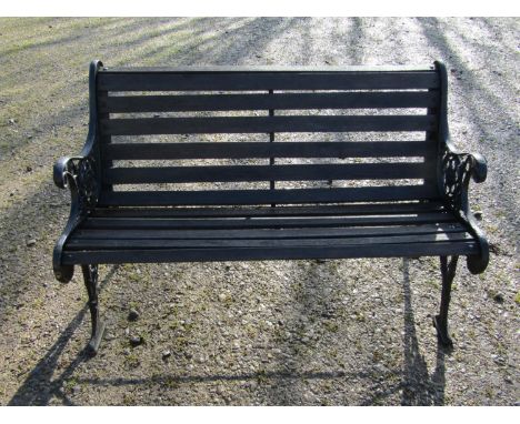 A two seat garden bench with stained wooden slatted seat raised on decorative pierced and scrolled cast iron end supports, 12