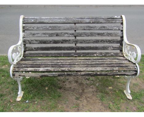 A two seat garden bench with slatted seat and combined back raised on painted cast iron scroll pattern stylised dolphin suppo