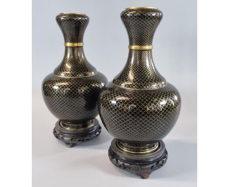 Pair of Oriental cloisonné baluster vases on a black ground with yellow metal fish scales design, on stands.  26cm high appro