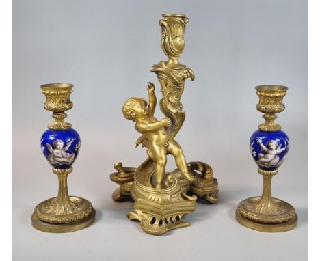 Baroque style bronze ormolu cherub candle stick, together with a pair of gilded candlesticks with central porcelain depiction