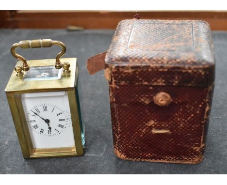 A gilt brass small carriage clock, white enamel dial with Roman numerals,&nbsp; the case with shaped handle over rectangular 