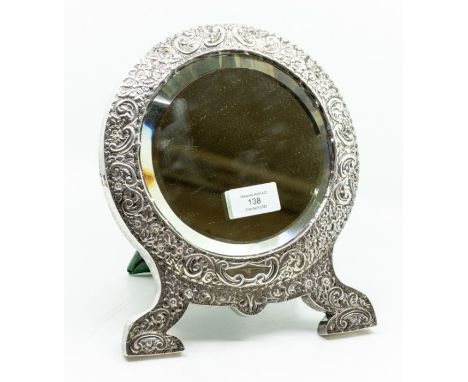 An Edwardian silver mounted easel mirror, the circular beveled glass surrounded by a silver frame embossed with foliate scrol