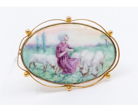 An Edwardian painted enamel and 9ct gold&nbsp; brooch featuring a young woman and sheep, within a bead and scroll open border