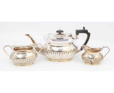 A George V silver three piece tea service, comprising teapot, milk jug and sugar bowl, gadroon lower section, carved ebony ha