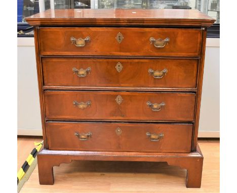 A George III veneered chest of four drawers on bracket feet with brass swing-handles (not original walnut veneer)