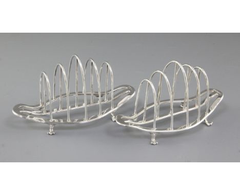 A pair of George V silver toast racks, by George Howson, hallmarked Sheffield 1930, of boat shape, on four paw feet, Length 1