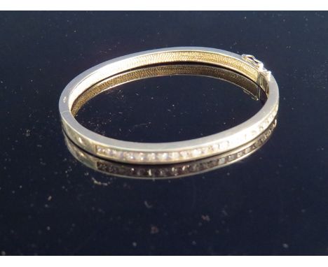A stiff hinge bangle with cubic zirconia stones, stamped 