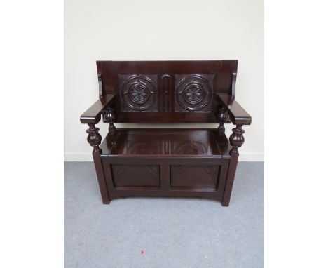 An Arts & Crafts mahogany monk's hall bench with carved Gothic decoration to back rest on turned supports and hinged seat box