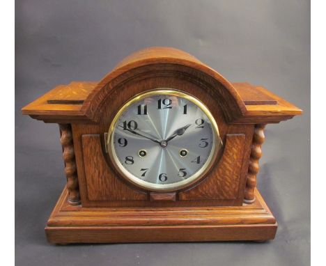 An oak mantel clock with barley twist columns, silvered Arabic numerated dial, 8-day movement 