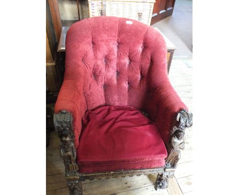 A Victorian Oak tub chair with maroon button back upholstery, carved with lion mask and figures, on leaf and lion mask carved