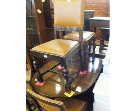 An oval Oak gate leg table and four tan leather upholstered dining chairs