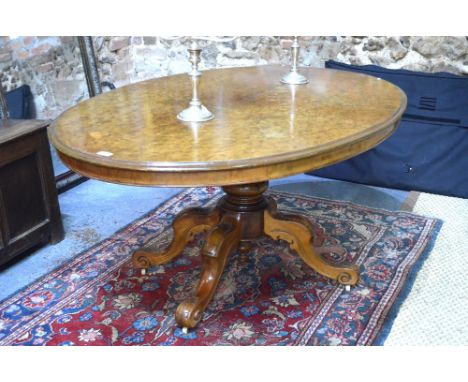 A Victorian burr walnut veneered breakfast table, the ovoid tilt top raised on a turned support to hip carved and swept quad 