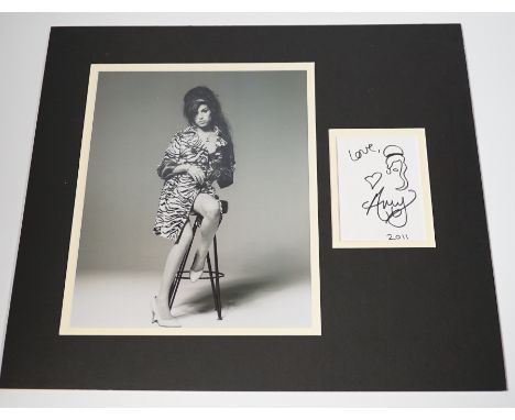 Amy Winehouse, an autograph with caricature self portrait dated 2011, mounted with a black and white portrait photograph Good