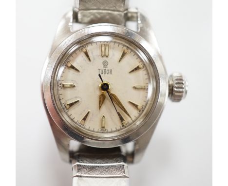 A lady's stainless steel Tudor manual wind wrist watch, with baton numerals, on an associated flexible bracelet.