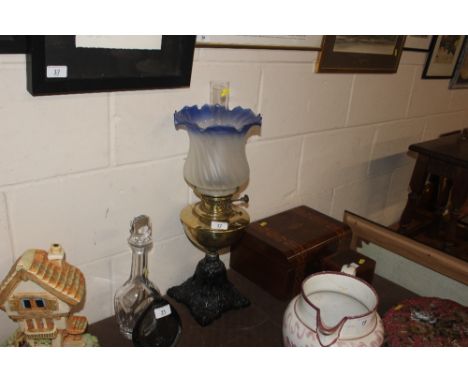 A brass and cast iron oil lamp with blue tinted shade 