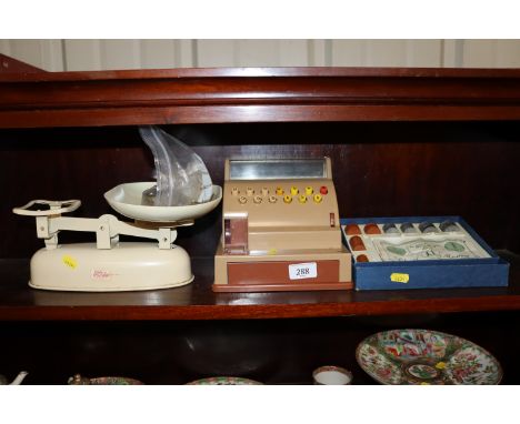 A toy plastic till, a box of school money and a set of scales 