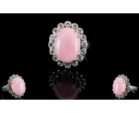 Pink Opal and White Topaz Halo Ring, a 9ct oval cut cabochon of pink opal framed with .75ct of individually bezel set, round 