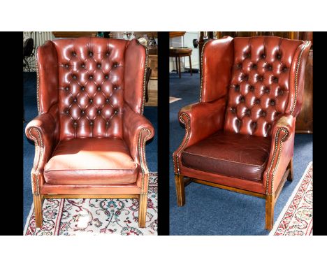 A Pair of Leather Club Chairs. Two wing-backed armchairs with traditional button back detail upholstered in oxblood leather f