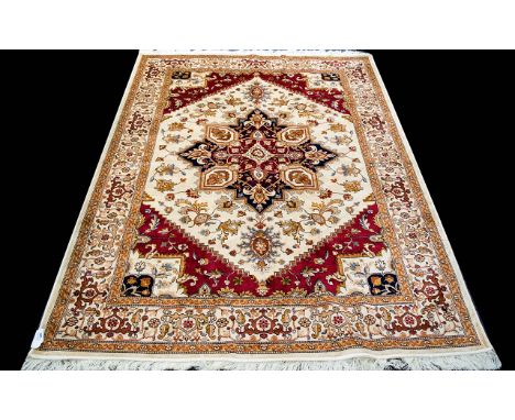 A Large Woven Silk Heriz Carpet Finley woven rug on beige ground with intricate scrolling floral and foliate design in red, b