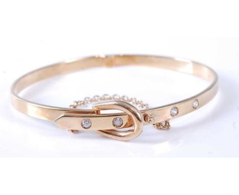 A 9ct yellow gold hinged oval buckle style bangle, having four round faceted colourless sapphires flush set and fitted with a