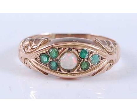 An Edwardian 9ct yellow gold, opal and emerald dress ring, featuring a centre round opal cabochon flanked on either side by a