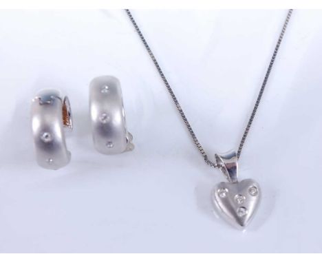 A white gold diamond pendant and earring set, the pendant comprising a satin finish heart set with four round brilliant cut d